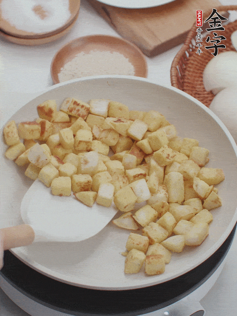 起鍋熱油，倒入饅頭丁，小火煎至蛋液凝固定型再翻面，饅頭丁部煎至金黃時(shí)盛起待用。